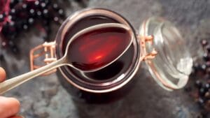 A person holding a spoon full of elderberry extract. They are getting ready to find out what does elderberry taste like