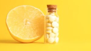 A freshly cut lemon with some vitamin C tablets in the foreground. Vibrant yellow to showcase the link between vitamin C and immune function.