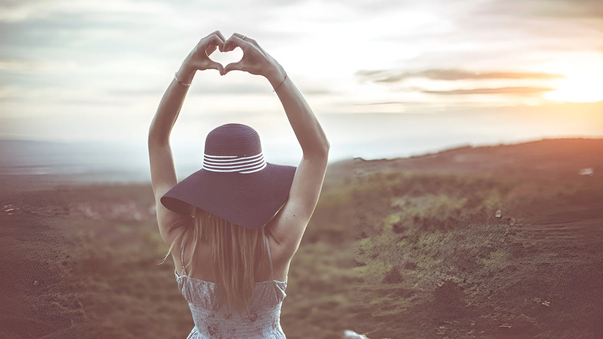 Pretty woman putting up her hands in a heart shape. She is outside in the afternoon light getting some vitamin D for energy.